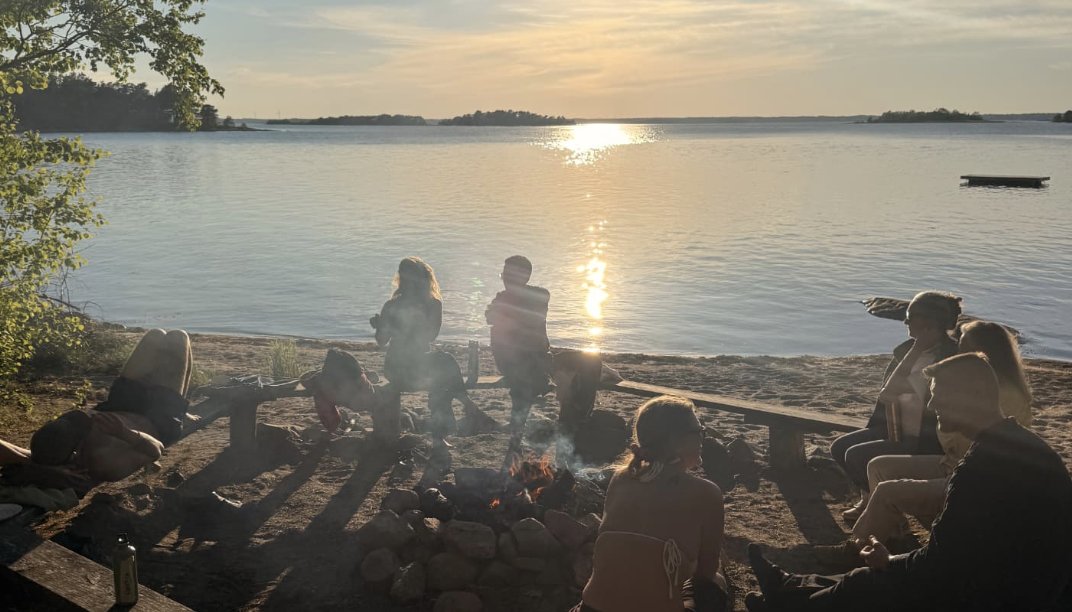 Gathered around a fire on the beach at sunset
